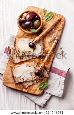 Sandwiches with Parmesan cheese and olives on olive wood cutting board