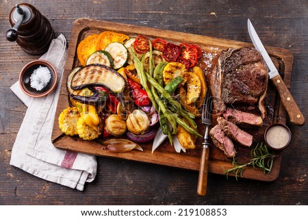 Club Beef steak with pepper sauce and Grilled vegetables on cutting board on dark wooden background