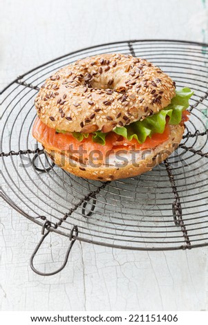 Salmon Bagel Sandwich with cream cheese and grain on blue wooden background