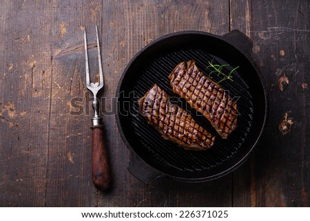 Grilled Striploin steak on grill pan on wooden background