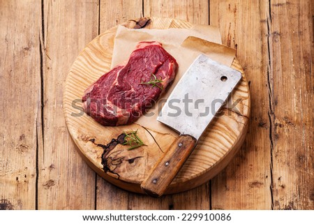 Raw fresh meat Ribeye Steak and meat cleaver on wooden background
