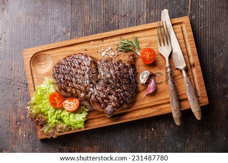 Medium rare grilled Beef steak Ribeye on cutting board on wooden background