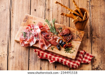 Cold meat plate and bread sticks on wooden background