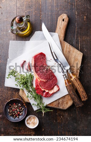 Raw fresh meat Ribeye steak entrecote and seasonings on cutting board on dark wooden background