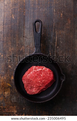 Raw meat Ribeye steak on cast iron frying pan on dark wooden background