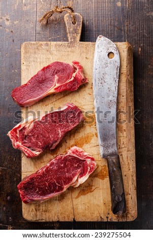 Raw fresh meat Ribeye steak entrecote and meat cleaver on cutting board on wooden background