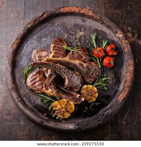 Roasted lamb ribs with spices and garlic on dark textural background