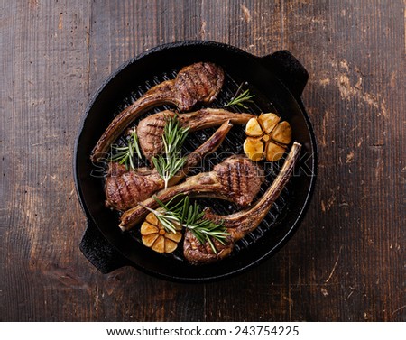 Roasted lamb ribs with rosemary and garlic on grill pan on dark background
