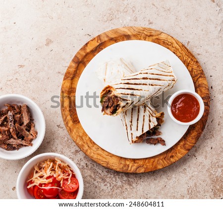 Doner Kebab grilled meat and vegetables on stone textured background