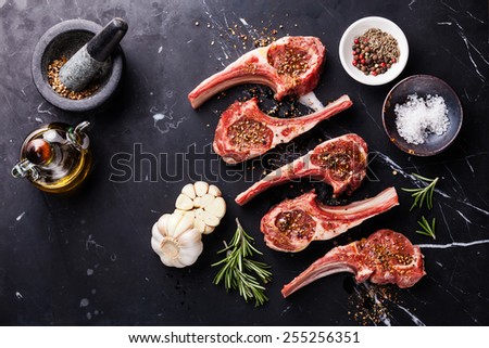 Raw meat mutton lamb ribs with herbs on black marble background