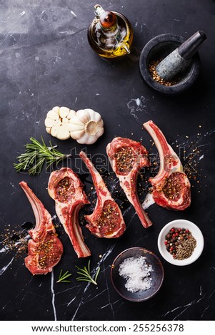 Raw meat mutton lamb ribs with herbs on black marble background