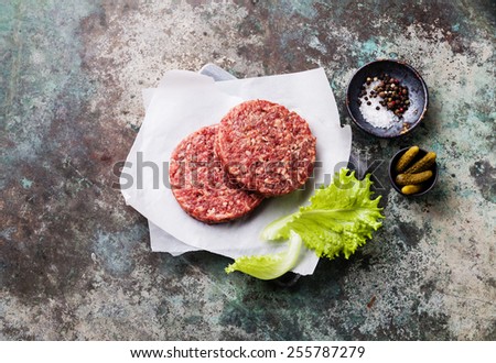 Raw Ground beef meat Burger steak cutlets and seasonings on metal background
