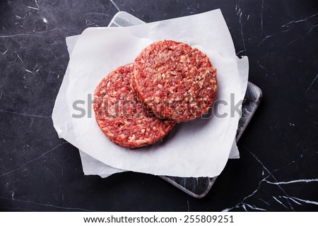Raw Ground beef meat Burger steak cutlets on dark marble background