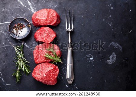 Raw fresh marbled meat Steak, seasonings and meat fork on dark marble background