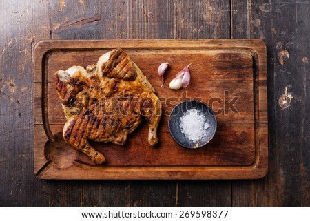 Grilled fried roast Chicken tobacco on cutting board on dark wooden background