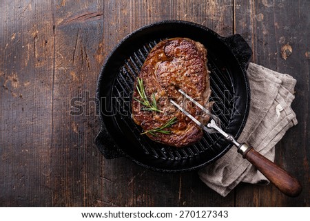 Grilled Black Angus Steak and meat fork on grill iron pan on wooden background