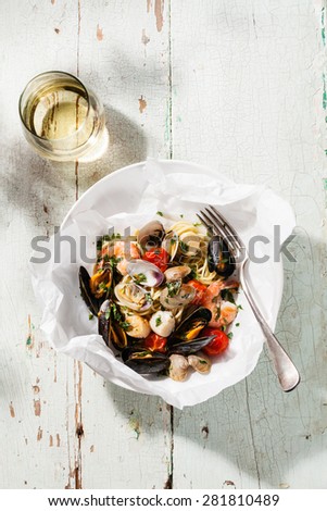 Seafood pasta and wine - Spaghetti with clams, prawns, sea scallops on white plate