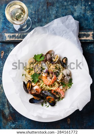 Seafood pasta and wine - Spaghetti with clams, prawns, sea scallops on blue background