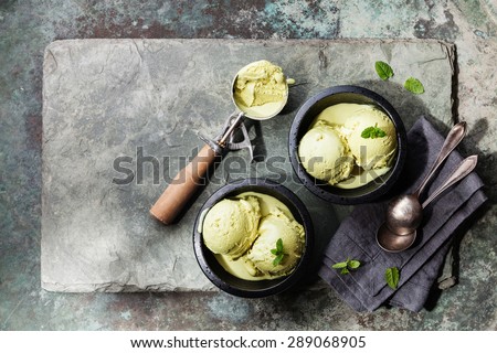 Green tea ice cream with mint leaves and Spoon for ice cream on stone slate background