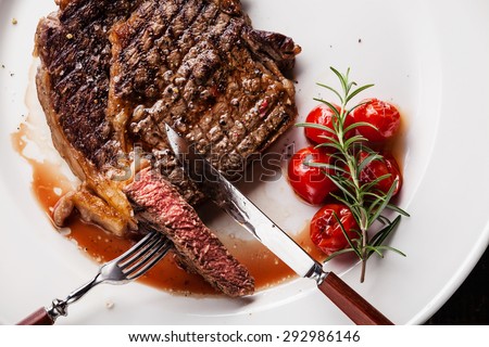 Sliced medium rare grilled Beef steak Ribeye with grilled cherry tomatoes on white plate background
