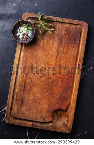 Chopping cutting board, seasonings and rosemary on dark marble background