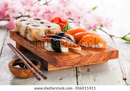 Sushi Set with sashimi and sushi rolls on olive wood board on blue wooden background