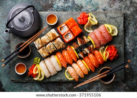 Sushi Set nigiri and sushi rolls with tea served on gray stone slate on metal background