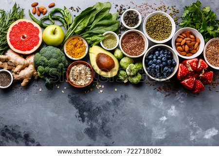 Healthy food clean eating selection: fruit, vegetable, seeds, superfood, cereals, leaf vegetable on gray concrete background copy space
