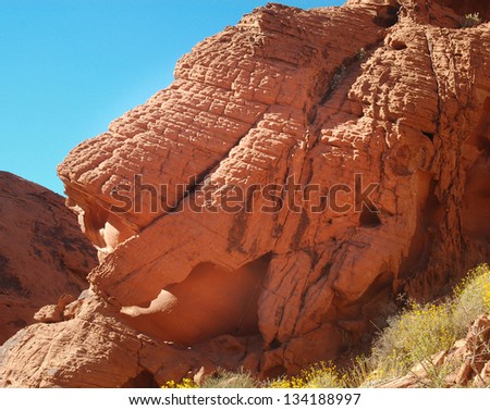 Red desert rock formation against a bright blue sky.