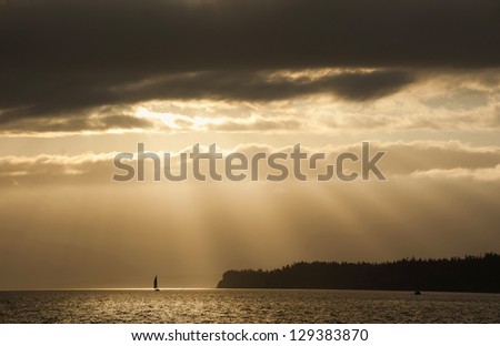 Sailboat Sunrise. Light rays shine down on an island near the historic town of Port Townsend, Washington, USA