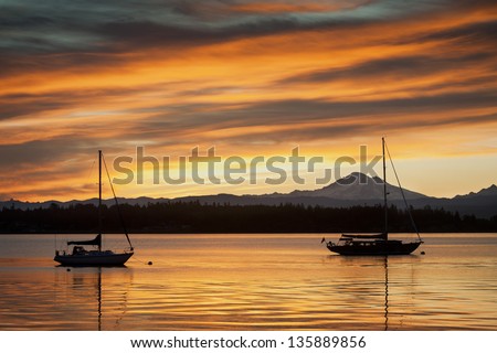 A sailboat anchors off of Lummi island, located in the San Juan Islands of the Puget Sound area of western Washington state. The volcano,Mt. Baker, can be seen in the background.