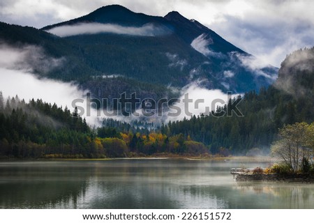 Ross Lake in Autumn. Low clouds and changing colors are a sure sign that fall is in full swing in the North Cascade mountains in this idyllic scene.