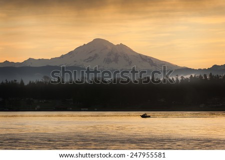 Fishing Boat and Mt. Baker. A sport fishing boat cruises past Mt. Baker in the Cascade Mountain range at sunrise in the Puget Sound area of western Washington state.