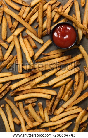 french fries and ketchup in a baking pan, top view, close up, vertical