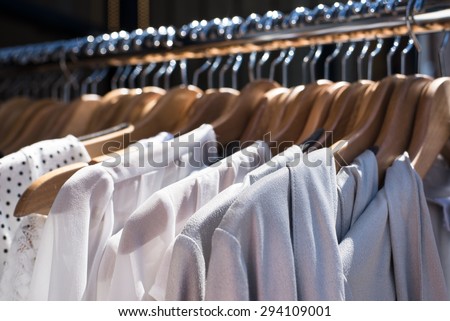 white and gray tone clothes hanging on a rack in a designer clothes store, selective focus, horizontal