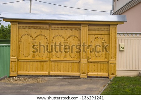 Facade with carvings old wooden fence and gates, made in Russian tradition in a country town