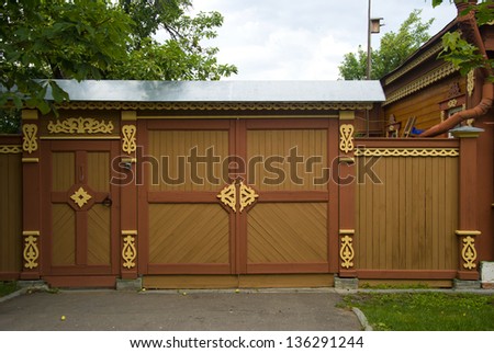 Facade with carvings old wooden fence and gates, made in Russian tradition in a country town