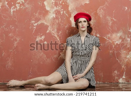 Cheerful young girl sitting on the floor vintage plaid dress and red beret