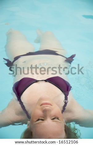 Girl floating on one\'s back in swimming pool