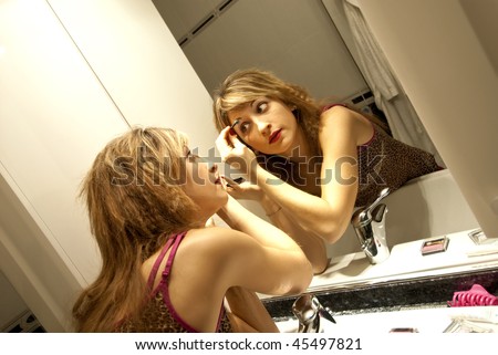 Beautiful Young Woman Making Up with Eyeshadow in front of the Dresser