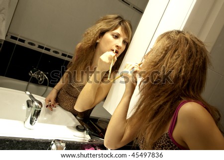 Beautiful Young Woman Making Up with Lip Liner in front of the Dresser