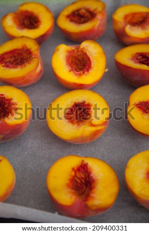 Halves of peaches on a baking paper, ready to baked.