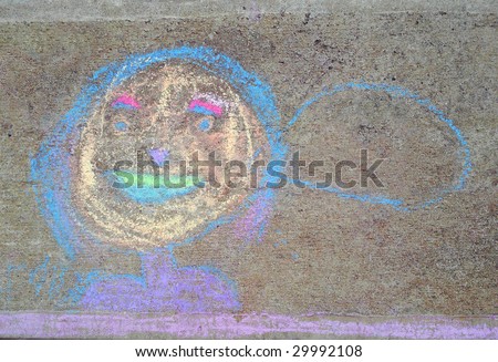 Child\'s chalk drawing of a smiling face with speech bubble on concrete.