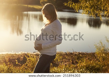 Beautiful mom to be in a park at sunset day during fall