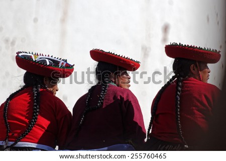 CHINCHERO, CUSCO/PERU - JANUARY 20, 2013: Women in their traditional cloths sitting on a stone wall in Chinchero in Peru.