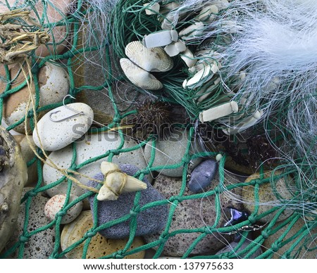 Sea background with fishing net and hooks on stones