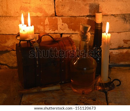 Retro bottles and old wooden box with burning candle in cellar background