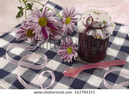 Jar jam with flowers and spoon on cute table napkin