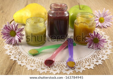 Baby food still life with pureed jars, spoons and fruit on napkin