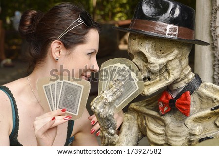 Pretty young girl playing cards with skeleton, Bangkok, Thailand